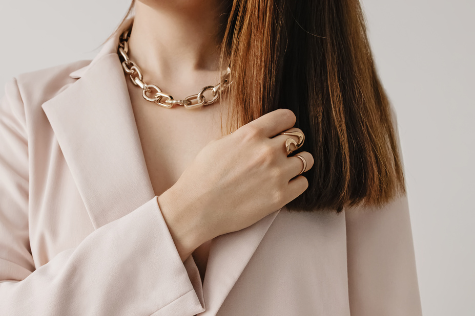 Woman in Light Beige Jacket Wearing Golden Chain Necklace.